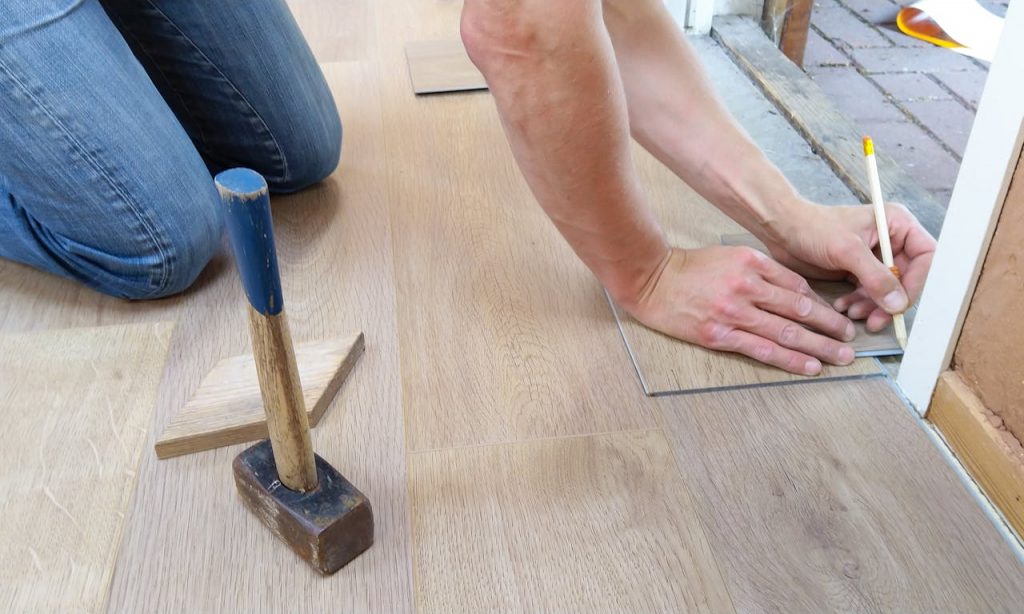 floor-flooring-hand-man-1388944 A craftsman carefully measures and marks wooden floor panels for precise installation.