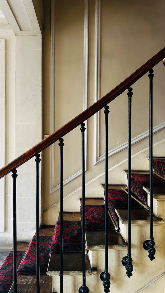A classic Parisian staircase with ornate iron railings and vintage decor, showcasing timeless elegance.